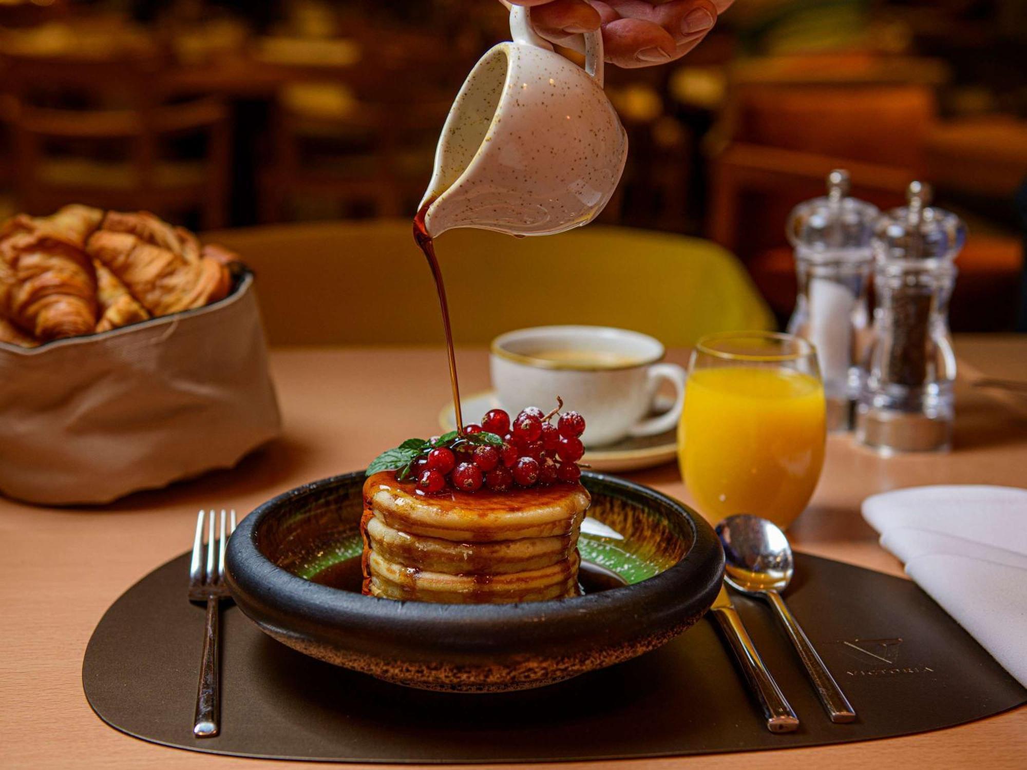 فندق سوفيتيل وارسو فيكتوريا المظهر الخارجي الصورة Maple syrup being poured over a stack of pancakes
